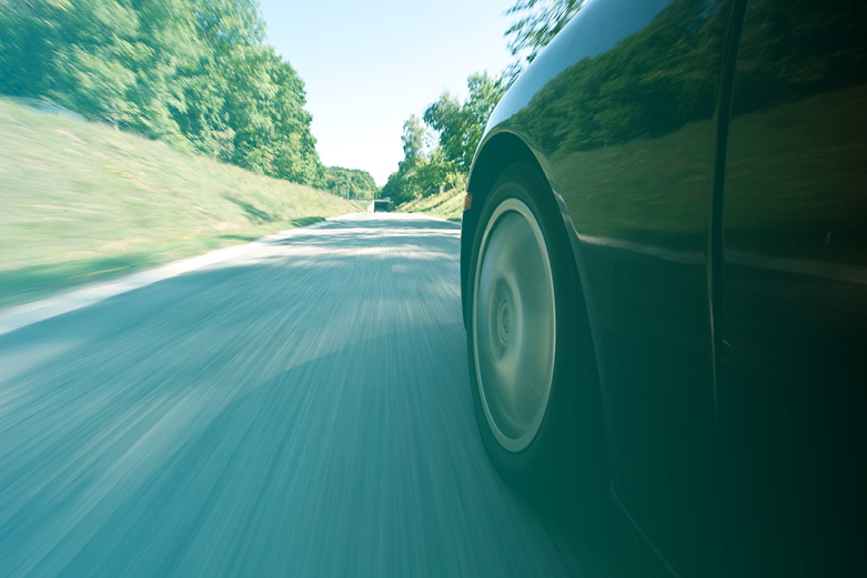 Nahaufnahme eines fahrenden Autos mit Blick auf die Straße